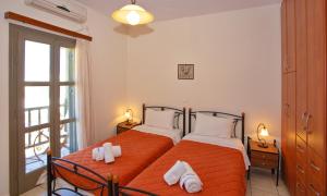 a bedroom with two beds with orange sheets and a window at To Pithari in Skiros