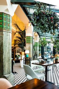 een restaurant met tafels, stoelen en planten bij Hotel Amsterdam De Roode Leeuw in Amsterdam