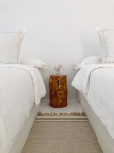 dos camas con sábanas blancas y un tronco de árbol entre ellas en CASA TAMATINA by Villitas, en Playa Blanca