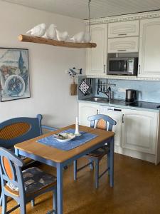a kitchen with a table and chairs and a kitchen with white cabinets at Haus Seeburg in Carolinensiel