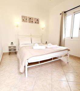 a bedroom with a white bed and a window at Avra Rooms in Karpathos