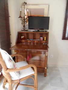 Habitación con escritorio, TV y silla. en villa Getty, en Cala en Forcat