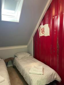 twee bedden in een kamer met een rode muur bij Tiny-House van zeecontainers bij het bos in Oranjewoud