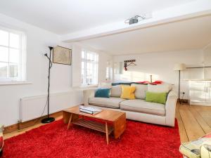 uma sala de estar com um sofá e um tapete vermelho em Lantern Cottage em Rye