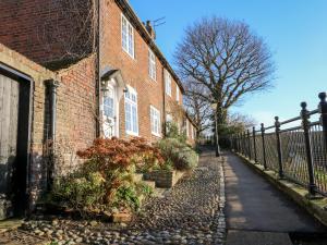a brick building with a fence next to a street at Lantern Cottage in Rye