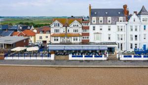 a group of buildings with tables and umbrellas in a town at The Brudenell in Aldeburgh