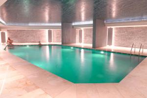 a swimming pool in a building with a person sitting in the background at Benesta Residence by NewInn in Istanbul