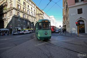 a green trolley car on a city street at Hotel Everest in Rome