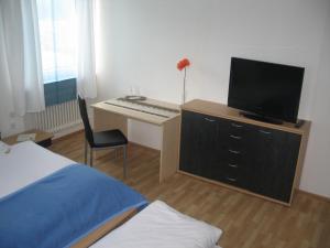 Schlafzimmer mit einem Schreibtisch, einem TV und einem Bett in der Unterkunft Gasthof-Pension Leupold in Selbitz