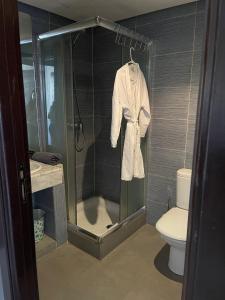 a bathroom with a shower with a white robe at Lovely one-bed flat with fiber optic and shared swimming pool in Agadir