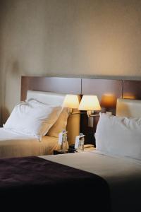 a hotel room with two beds and two lamps at Hotel Madero Buenos Aires in Buenos Aires