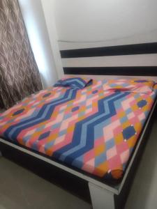 a bed with a colorful comforter on top of it at Sai Guest House in Pathānkot