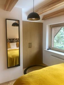 - une chambre avec un lit jaune et un miroir dans l'établissement Piękny apartament w Pieninach, à Krościenko nad Dunajcem