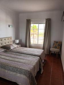 1 dormitorio con cama, ventana y silla en T1 Praia do Vau / Estrela do Vau en Portimão