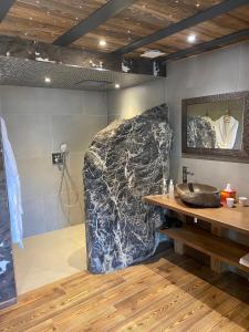 a bathroom with a sink and a large rock at Les Mazots des Fées in Morzine
