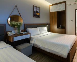 ein Hotelzimmer mit 2 Betten und einem Spiegel in der Unterkunft West Lake Hotel - Near Bai Dai Beach in Thủy Triều