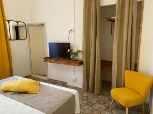 a bedroom with a bed and a yellow chair at BIANCA ROOMS in Noto