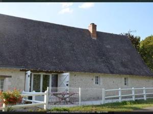 una casa con techo negro y valla blanca en LES GRANGES D'ANTAN - La FORGE -, en Chalonnes-sous-le-Lude