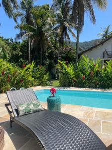 a table and a vase sitting next to a pool at Hospedaria do Marquês in Boicucanga