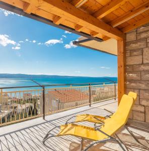una terraza con una silla amarilla y vistas al océano en Azra Apartments en Duće