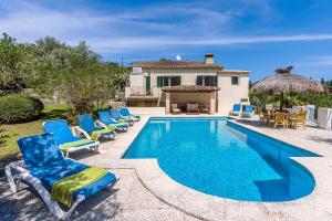 a swimming pool with blue chairs and a house at Villa La Coma in Pollença