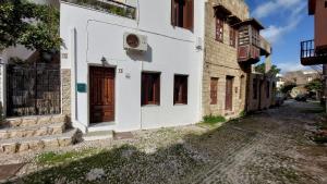 biały budynek z drewnianymi drzwiami na ulicy w obiekcie OLD TOWN TALES apartments w mieście Rodos