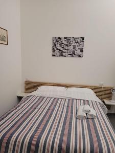 Una cama con una manta a rayas y dos toallas. en Zio Toto' en Bolonia