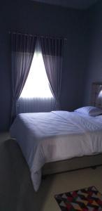 um quarto com uma cama branca e uma janela em Pintu Waluh Homestay em Takengon
