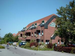 two people riding bikes in front of a brick building at Haus Seeburg in Carolinensiel