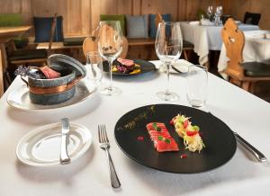 einen Tisch mit zwei Teller mit Speisen und Weingläsern in der Unterkunft Hotel Lac Salin Spa & Mountain Resort in Livigno