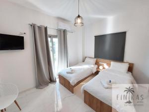 a room with two beds and a tv and a table at FINIKAS Suites & Apartments 10min from Athens Airport in Artemida