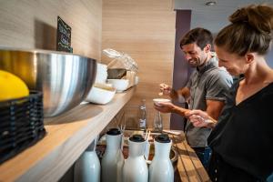 Résidence-Aïga Resort thermal & spa في شاتيل-جويْيو: رجل وامرأة يقفان في المطبخ مع المزهريات