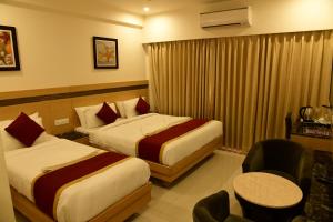 a hotel room with two beds and a chair at Hotel U.T.ELITE in Bangalore