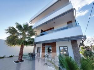 a villa with a palm tree in front of it at FINIKAS Suites & Apartments 10min from Athens Airport in Artemida