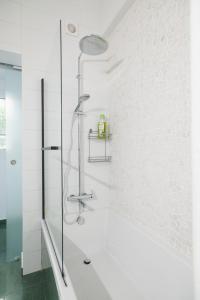 a shower in a white bathroom with a tub at Sunny Family Home By The Beach in Limassol
