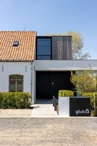 une maison blanche avec un garage noir dans l'établissement GLUK, à Zonnebeke