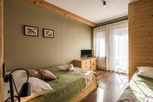 une chambre avec deux lits et une télévision et une fenêtre dans l'établissement Lux apartamenty Stara Polana, à Zakopane 44 autres photos