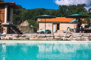 a swimming pool with two umbrellas and a house at Casas da Fraga 2020 in Ribeira de Pena