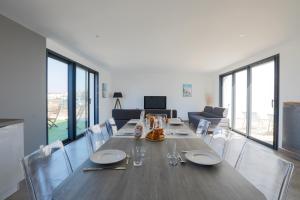 uma sala de jantar com uma mesa longa e cadeiras em Maison tout confort a deux pas de la piste cyclable em Le Bois-Plage-en-Ré