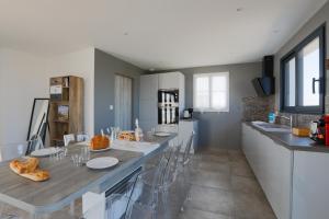 eine Küche mit einem Tisch und Stühlen im Zimmer in der Unterkunft Maison tout confort a deux pas de la piste cyclable in Le Bois-Plage-en-Ré