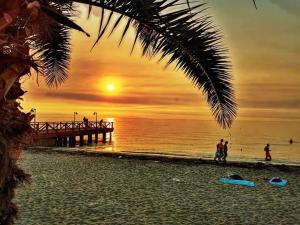 a beach with a pier and people standing on the beach at Villa Marili in Paralia Katerinis