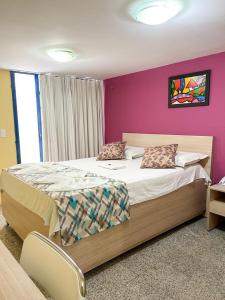 a bedroom with a large bed with a purple wall at Executivo Prime Hotel in Teresina