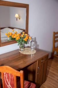 a table with a vase of flowers on it with a mirror at Weranda Rooms in Tychy