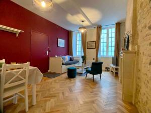 a living room with red walls and a wooden floor at Hello Bayeux - Confort dans le coeur de la ville in Bayeux