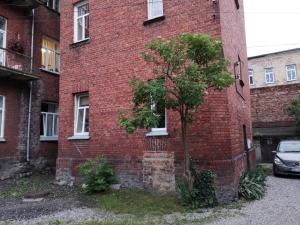 a red brick building with a tree in front of it at Sonata in Liepāja