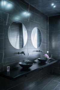 two sinks in a black bathroom with two mirrors at Marmur Suite in Palermo