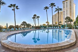 a swimming pool with chairs and palm trees at Beachfront Clearwater Condo with Community Pool in Clearwater Beach
