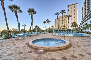 una bañera de hidromasaje en un patio con sillas y palmeras en Beachfront Clearwater Condo with Community Pool, en Clearwater Beach