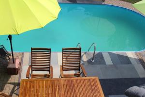 two chairs and an umbrella next to a swimming pool at Villa Bademeusel in Straupitz