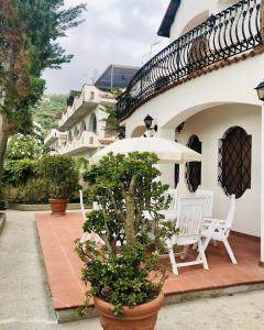 patio z 2 białymi krzesłami i parasolem w obiekcie Villa Luigina - seafront villa in Capo d'Orlando w mieście Capo dʼOrlando +37 zdjęć